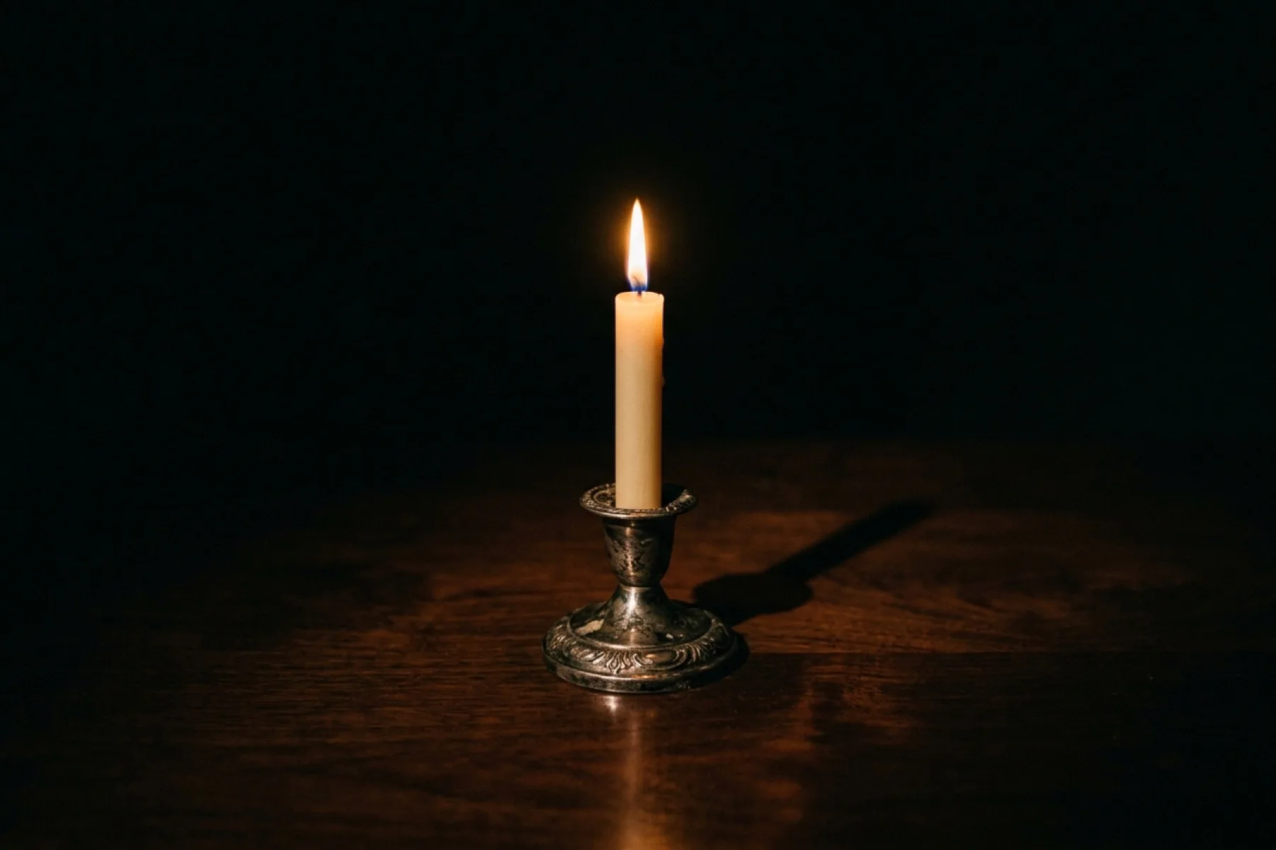 A small tea-light and a tall taper candle side by side in darkness — the controlled quiet flame and the full bright flame, the dynamic range from soft to forte